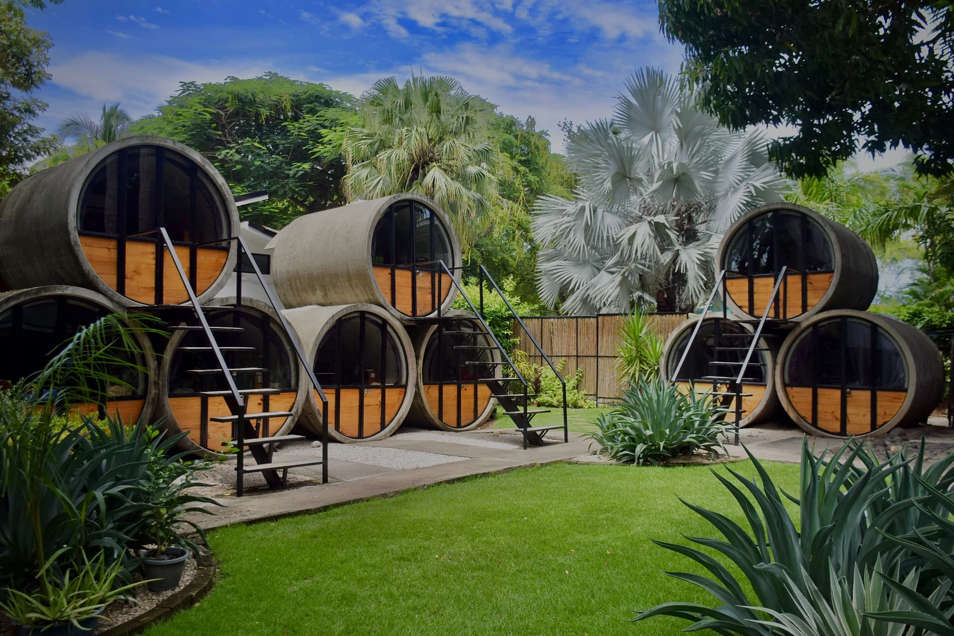 Rounded timber cabins set in a landscaped garden beneath steep mountains