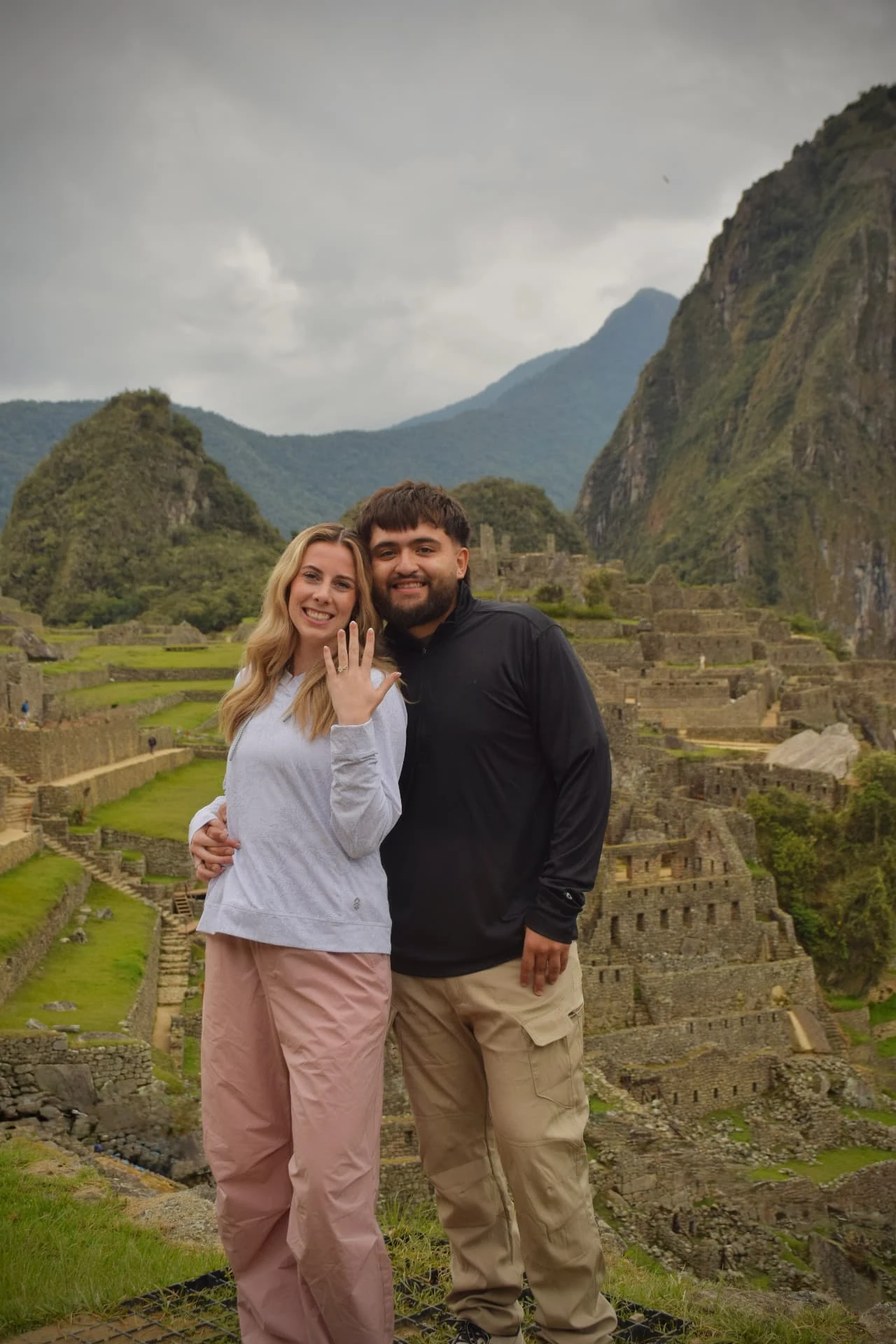 A couple standing among ancient stone terraces beneath dramatic mountains