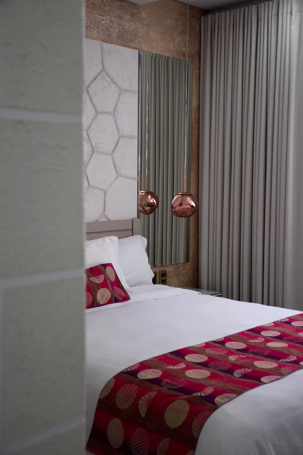 Bedroom framed by stone walls with soft curtains and patterned bedding