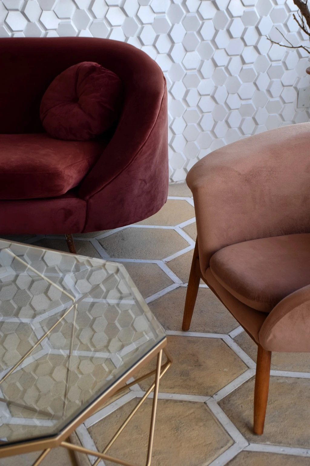 Burgundy and blush lounge chairs beside a geometric glass table